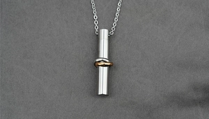 Macro detail of cylinder memorial urn necklace with golden rings and steel chain