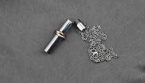 Detail of a stainless steel cylinder urn pendant with two-tone rings on a chain
