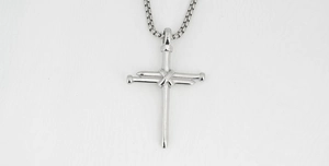 Macro detail of industrial nail cross pendant in polished steel with square box chain