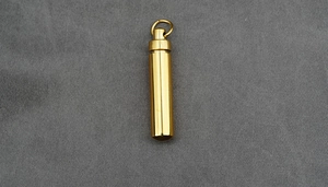 Detailed macro view of a gold-plated titanium steel cylindrical urn pendant with polished finish