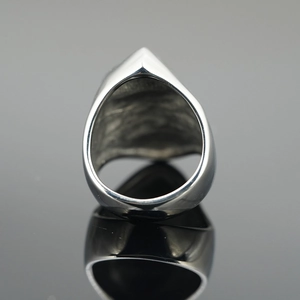 Gothic punk skull style ring with wide band and pointed top on reflective dark background