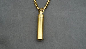 Close-up of golden cylindrical stainless steel perfume necklace with polished box chain