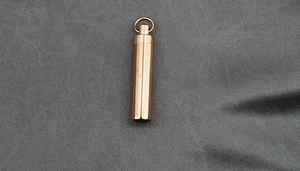 Close-up of rose gold stainless steel cylindrical cremation urn pendant for ashes
