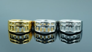 Detailed close-up showing three metal abacus rings in gold and silver on a mirror
