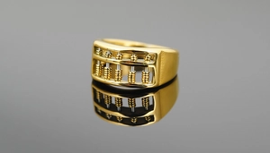 Macro detail of golden stainless steel abacus ring with movable beads on black reflection