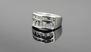 Macro shot of silver abacus ring with movable beads on reflective dark background