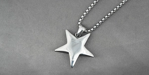 Close-up of a silver pentagram star pendant with polished finish on a box chain