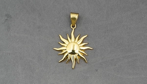 Detailed view of a golden sunflower pendant with high polish finish on grey fabric