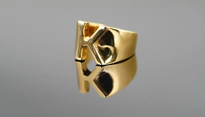Vue macro d'une bague large dorée polie avec un design audacieux de la lettre K