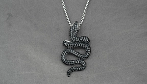 Detailed view of S-shaped rattlesnake pendant with black crystals on a silver chain