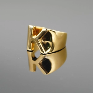 Bague dorée polie avec la lettre K pour hommes et femmes sur surface sombre