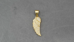 Macro detail of a golden angel wing pendant encrusted with sparkling crystals and stones