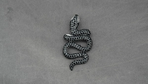 Macro shot of S-shaped rattlesnake pendant with black crystals and detailed craftsmanship