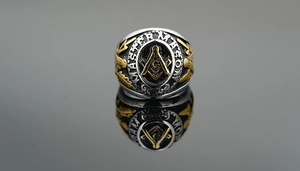 Detail of Master Mason ring with embossed Freemason symbol and gold finish on black surface