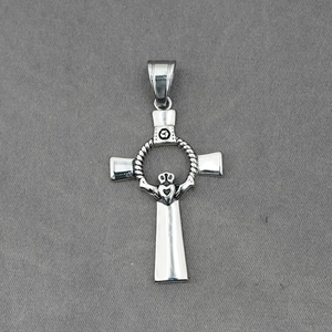Vintage silver Celtic cross pendant with Claddagh heart and triskele on grey fabric