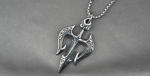 Macro detail of silver trident pendant with vintage embossed vine patterns and box chain