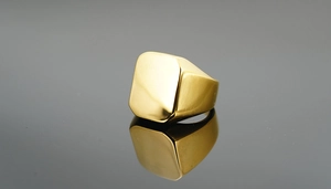 Gros plan détaillé d'une bague chevalière carrée en or poli sur une surface réfléchissante