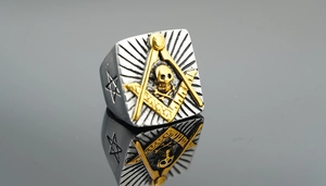 Detail view of two-tone Masonic skull ring with square and compass symbol on mirror surface