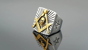 Detailed close-up of a silver and gold Masonic signet ring with skull and star motifs