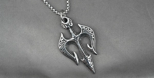 Macro detail of vintage silver trident pendant with intricate sea wave engravings on chain