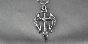 Detailed macro view of vintage trident pendant with intricate scrollwork engraving