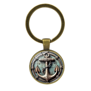 Vintage bronze anchor keychain with nautical motif in glass dome pendant on white background