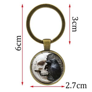 Gothic metal keychain featuring a dark crow and skull pendant in vintage bronze finish