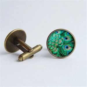 Detail of vintage bronze cufflinks with peacock feather glass dome and bullet back closure