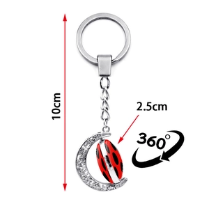 Detail view of rotating moon keychain with red ladybug pattern and 360 degree spin function