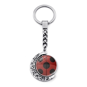 Macro detail of rotating ladybug charm on silver crescent moon keychain with glass dome