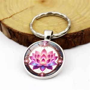 Detailed close-up of a silver lotus keychain pendant on a rustic wooden background