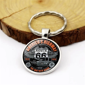 Close-up of Route 66 keychain with vintage hot rod design on a rustic wooden surface