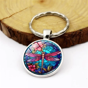 Macro view of a round dragonfly pendant keychain with colorful stained glass art pattern