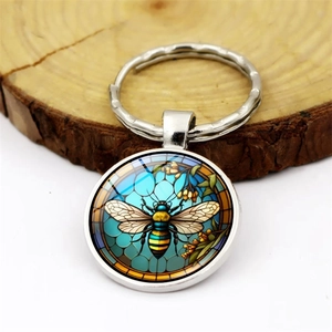 Macro shot of a round silver keychain featuring a detailed bee on stained glass art