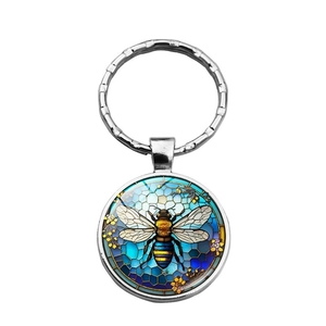 Detail of bee and floral pattern under glass on a circular metal keychain charm
