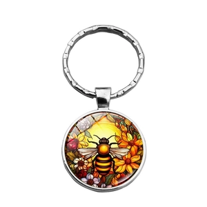 Detail showing the bee and flower pattern on a silver metal keychain charm