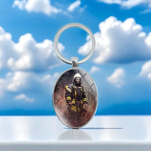 Detailed macro view of the oval metal keychain featuring a brave firefighter design