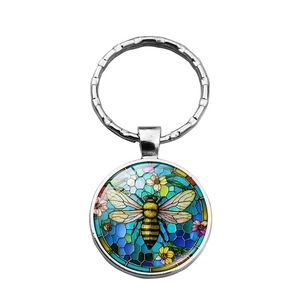 Close-up of circular bee and flower pattern keychain with polished silver metal ring
