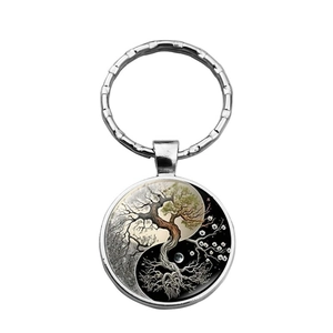 Macro detail of Yin Yang Tree of Life glass cabochon pendant on silver metal keychain