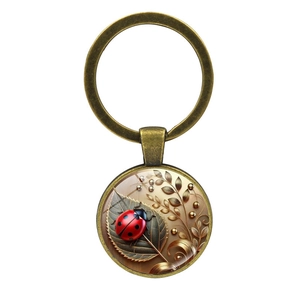 Vintage ladybug keychain with red beetle on leaf pattern and bronze metal ring