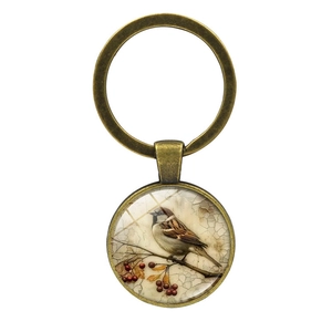 Vintage bronze keychain with round glass pendant featuring bird on branch illustration