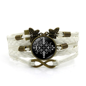 Detail eines mehrlagigen Webarmbands mit mystischem Symbol, Infinity-Zeichen und Schmetterling
