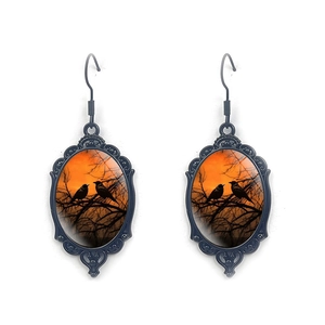 Gothic style oval drop earrings featuring black silhouettes of birds on branches at sunset