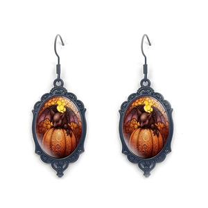 Close-up of gothic Halloween earrings featuring a black bat on an orange pumpkin pendant