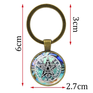 Vintage bronze pentagram keychain with occult symbols on iridescent background