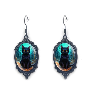 Detail of gothic oval earrings with black cat, pumpkin, and graveyard pattern