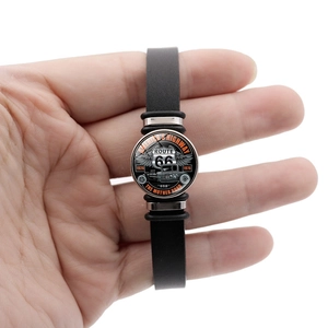 Détail du bracelet en cuir noir Route 66 avec emblème en métal vintage et boutons