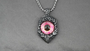 Close-up of punk style stainless steel necklace pendant with a pink evil eye detail