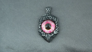 Close-up of a punk style evil eye pendant with purple iris and hammered steel texture