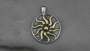 Macro detail of sunburst pendant showing golden spiral rays and fine wave textures
